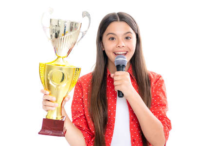 Girl with win cup microphone speech. Teen holding a trophy. Kid winner child won the competition, celebrating success and victory. Portrait of happy smiling teenage child girl.の写真素材