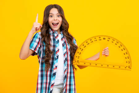 Amazed teen girl. Back to school. School girl hold ruler measuring isolated on yellow background. Excited expression, cheerful and glad.の写真素材