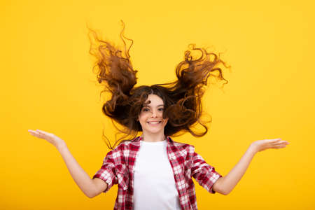 Teenager face with crazy movement hair. Young teen child with flowing hair. Brunette teen girl fluttering hair in motion. Happy teenager, positive and smiling emotions of teen girl.の写真素材