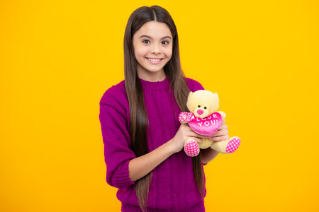 Teen with toy teddy bear with love heart for valentines day. Childhood, toys and kids. Cute teen girl cuddling fluffy toy.の写真素材