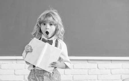 amazed child boy in bow tie study in school classrrom with notebook, copy space, back to school