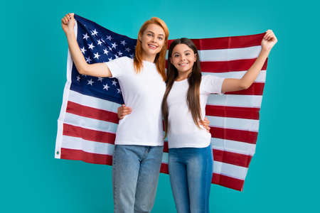 Patriotic holiday. Happy family, mother and daughter with American flag on blue isolated studio...