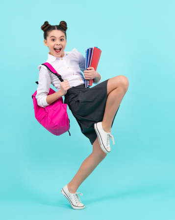 Amazed teenager. School teenage girl with book and copybook. Teenager schoolgirl student, isolated background. Learning and knowledge. Crazy jump and run, jumping kids.の写真素材
