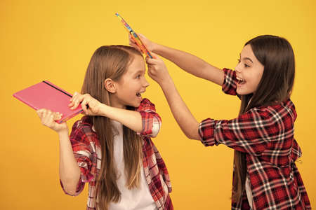 happy teen girls in checkered shirt playing with notebooks, positive emotions