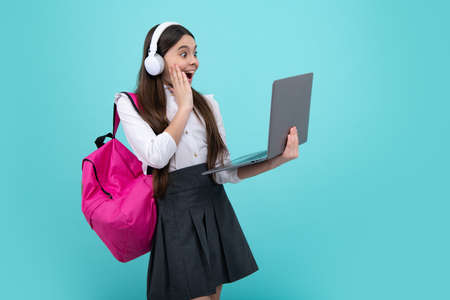 Back to school. Happy teenager school girl in school uniform with bagpack, headphones and laptop....