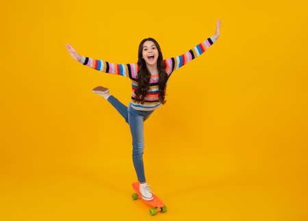 Teen girl 12, 13, 14 years old with skateboard over studio background. Cool modern teenager in...