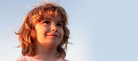 Face of happy boy child smiling sky background, portrait. Horizontal poster design. Web banner header, copy space.の写真素材