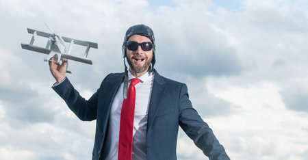 glad businessman in suit and pilot hat launch plane toyの写真素材