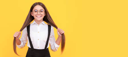 cheerful kid hold long hair in school uniform and glasses for vision protection, hair. Child face, horizontal poster, teenager girl isolated portrait, banner with copy space.の写真素材