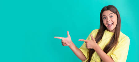 amazed child pointing fingers on blue background with copy space, amazement. Child face, horizontal poster, teenager girl isolated portrait, banner with copy space.の写真素材