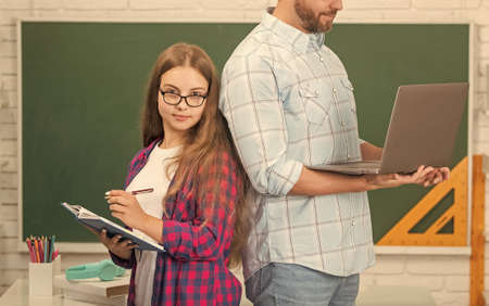 cropped father and child school with book and laptop on blackboard background, online lesson.の写真素材