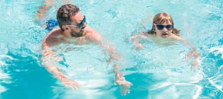 Father and son in swimming pool, banner with copy space. father and son wear glasses in swimming...