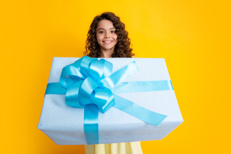 Teenager child with gift box. Present for holidays. Happy birthday, Valentines day, New Year or Christmas. Kid hold present box. Happy curly teenager portrait of smiling girl.の写真素材