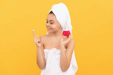 happy teen child in shower towel applying facial creamの写真素材