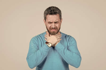 pain in throat. suffering man in has grizzled hair. sick man on grey background. mens health.の写真素材