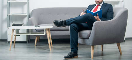 busy mature businessman in suit sit in office reading bookの写真素材