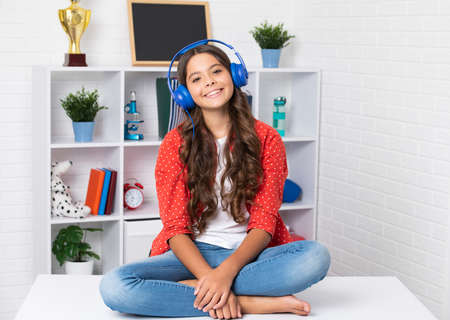 Teenager schoolgirl listening music. Portrait of teen with headphone. Children, music, emotions concept. Excited child school girl.の写真素材