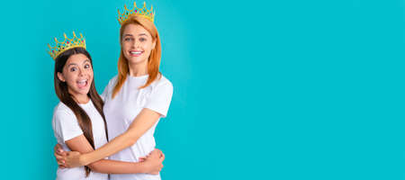Mother and daughter child banner, copy space, isolated background. Happy woman and girl child in crowns hug smiling blue background, mother.の写真素材