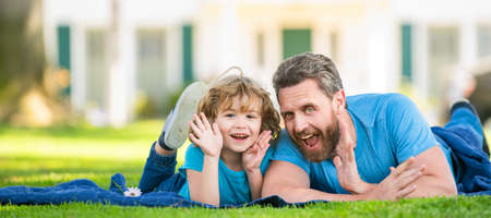 Banner of father and son in summer park outdoor. family value. childhood and parenthood. parent relax with little child boy on grass.の写真素材