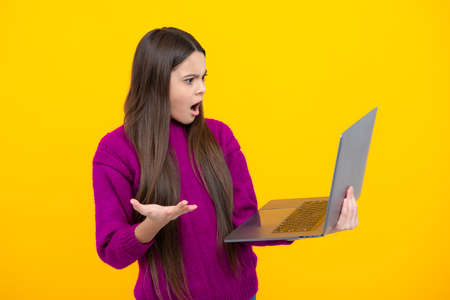Young girl student hold computer. Funny pupil with laptop isolated on yellow background. Back to...