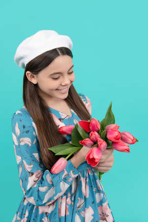happy child in beret holding tulips. mothers or womens day. kid hold flowers for 8 of march.の写真素材