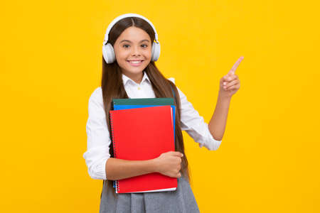Schoolgirl with copy book posing on isolated background. Literature lesson, grammar school. Intellectual child reader. Happy girl face, positive and smiling emotions.の写真素材
