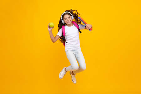 Back to school. Schoolgirl student in headphones with school bag backpack hold book on isolated...