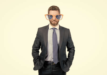 Serious professional man in funny sunglasses and formal suit with hands in pockets, businessman