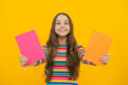 Teen girl pupil hold books, notebooks, isolated on yellow background, copy space. Back to school,...