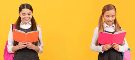 School girls friends. Little children in school uniforms read library books yellow background, reading. Banner of school girl student. Schoolgirl pupil portrait with copy space.の写真素材