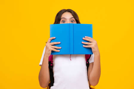 School teenage girl with school bag backpack hold book on yellow isolated studio background. Children school and education concept.の写真素材