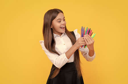 Happy girl child hold felt-tips yellow background, school stationeryの写真素材