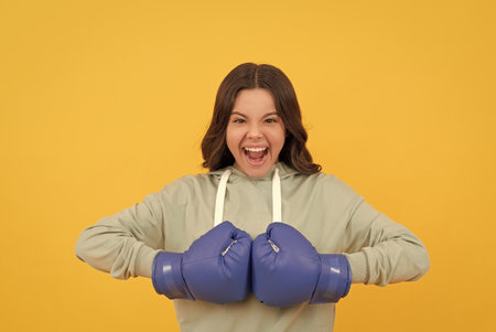 shouting child in boxing gloves on yellow background, sportの写真素材