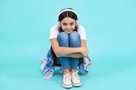 Teen girl in headphones listen to music. Wireless headset device accessory. Child enjoys the music in earphones on yellow background. Happy casual teenager. Urban kids style, stylish hipster teen.の写真素材