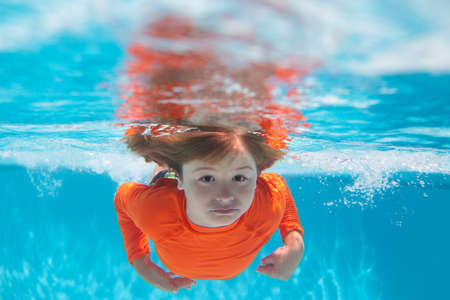 Kid boy swim underwater in sea. Kid swimming in pool under water. Active kid swimming, playing and diving, children water sport.の写真素材