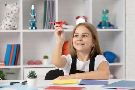 positive child play with paper plane in school classroom