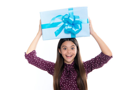 Child with gift present box on isolated studio background. Gifting for kids birthday. Portrait of happy smiling teenage girl.の写真素材
