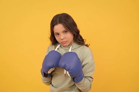 serious child portrait in boxing gloves on yellow backgroundの写真素材