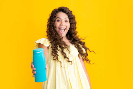 Teenager child girl with bottle shampoo conditioners or shower gel. Kids hair care. Hair cosmetic product, shampoo bottle. Excited teenager, glad amazed and overjoyed emotions.の写真素材