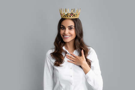 Young lovely woman in crown on gray background. Girl with queen crown celebrating win. Winner concept.の写真素材