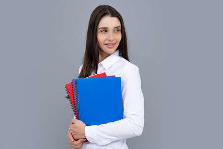 Young student girl in casual clothes, isolated on gray background studio portrait. Hold notebooks....