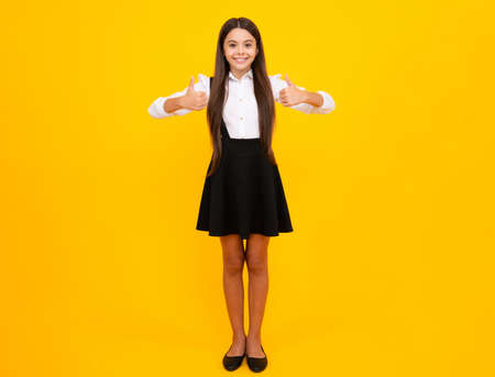 School uniform. Full length of her she attractive pretty lovely cute cheerful cheery teenager child girl isolated over vivid yellow background. Mock up copy space.の写真素材