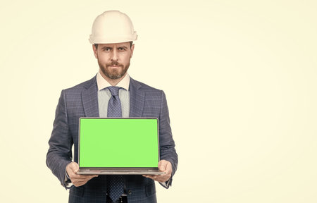businessman man in suit and safety helmet showing green screen of laptop copy space, presentation.