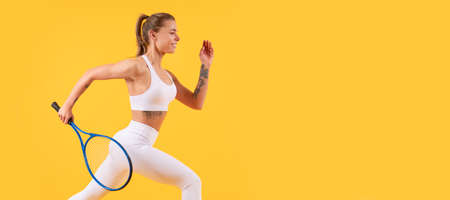 happy tennis player running with racket on yellow background, badminton. Woman isolated face portrait, banner with mock up copyspace.の写真素材