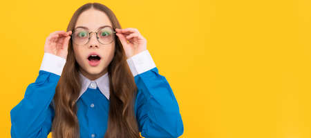 Shocked school aged girl child in spectacles with amazed look yellow background, amazement. Child face, horizontal poster, teenager girl isolated portrait, banner with copy space.の写真素材