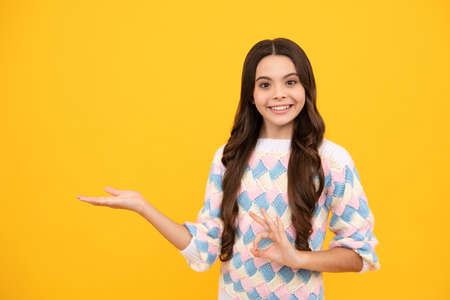 Impressed teenage girl showing recommendation copyspace. Child teenager points away, pointing aside at copy space.の写真素材
