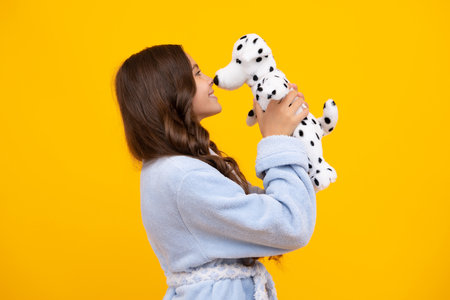 Child in pajamas, good morning. Teenager child girl in holding plush toy isolated on yellow background, happy childhood.の写真素材