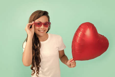 happy child in sunglasses hold red heart party balloon for valentines day love symbol, love dayの写真素材