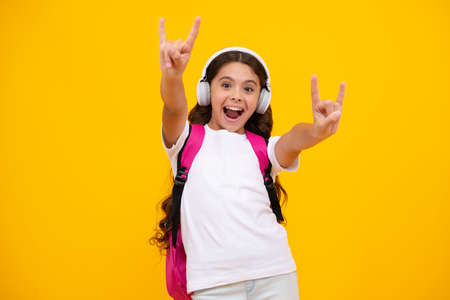 Amazed teen girl. with backpack hold aplle ready to learn. School children with school bag on isolated yellow studio background. Excited expression, cheerful and glad.の写真素材