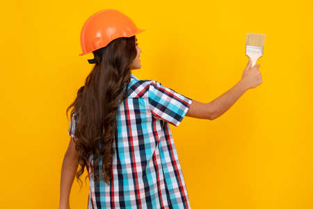 Renovation for childrens room. Little girl in protective helmet and paint brush for painting walls.の写真素材